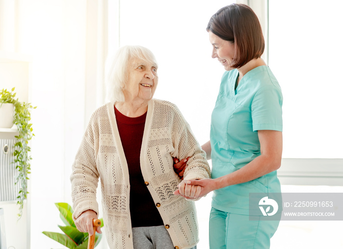 Caregiver helping elderly woman to walk