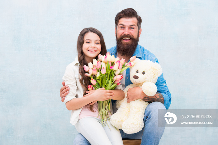 dad and girl child embrace with spring tulip flower bouquet and teddy bear toy, childrens day