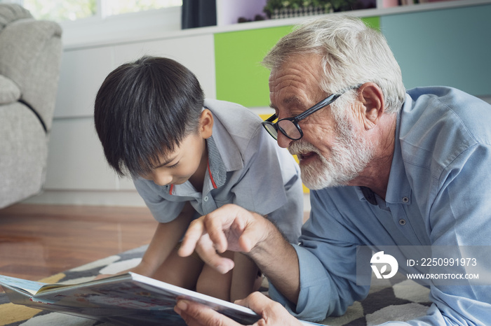 senior man happiness and grandson are sitting on the floor and playing games and reading book at liv