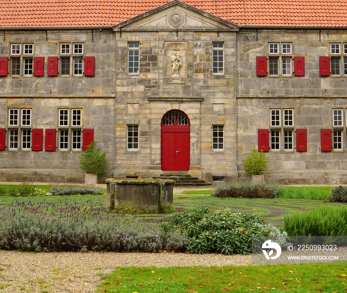 Fassade eines alten Klosters in Deutschland. Schöne rote Fensterläden. Ein Brunnen vorne und das rek