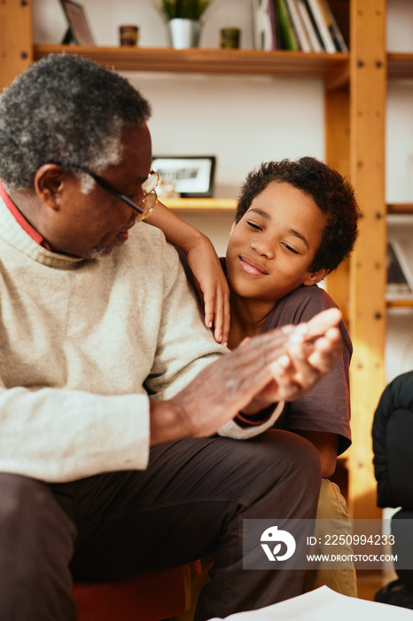 Proud grandfather clapping his hands and congratulating his grandson for perfectly done homework. Th