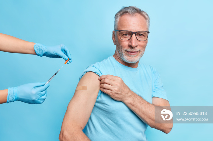 Vaccination for old people. Bearded grey haired European man gets inoculation against coronavirus di