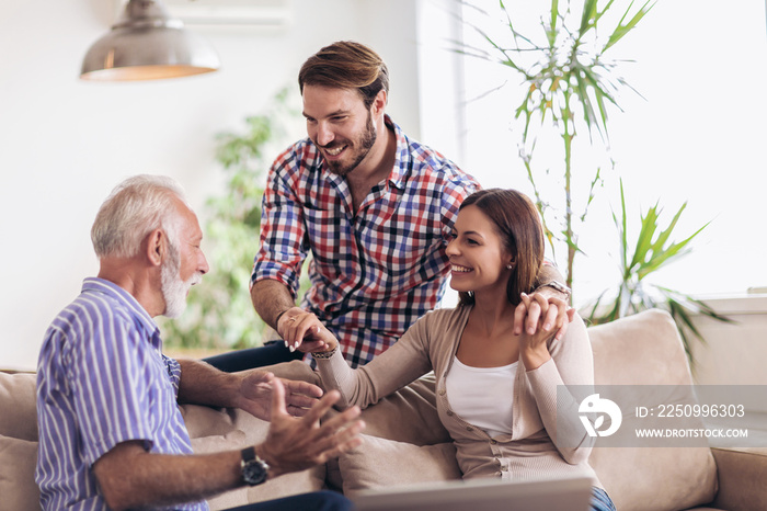 Young couple talking with their senior father at home