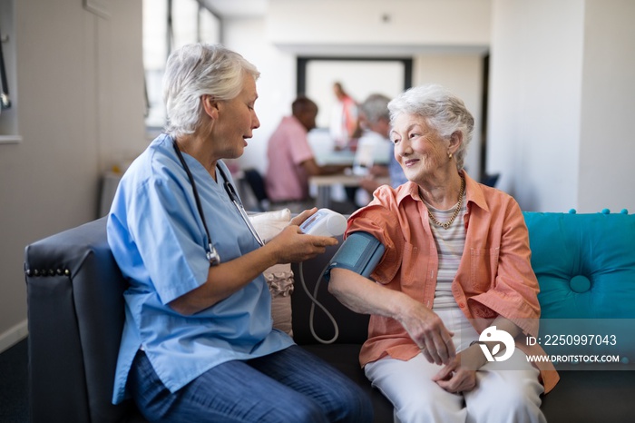 Nurse checking senior woman blood pressure at nursing home