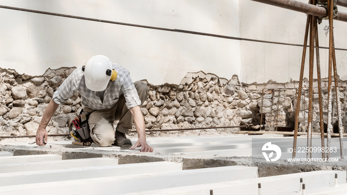 man at work, construction worker wear a helmet, check the measurements and distances of the beams at