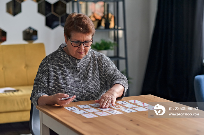 senior woman playing solitaire at home. Happy old lady plays an intellectual game