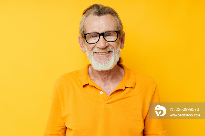 Portrait of happy senior man wearing glasses yellow shirt posing unaltered