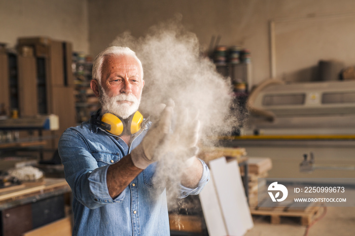 Carpenter removing dust from gloves