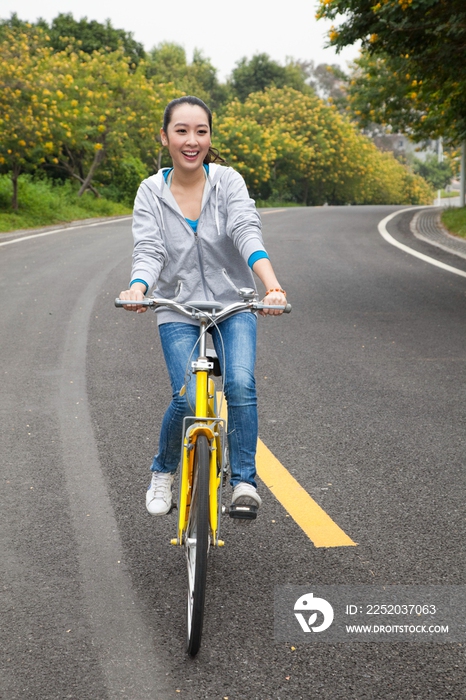 一个年轻女大学生在校园里骑车