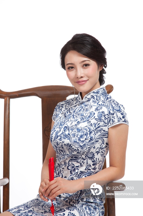 棚拍身穿中国传统服装的年轻女人坐中式椅