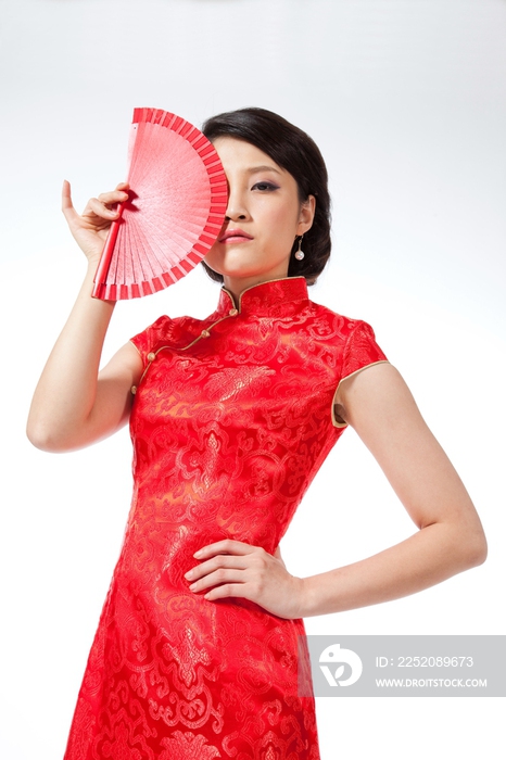 棚拍节日身穿红色旗袍的年轻女人拿着扇子