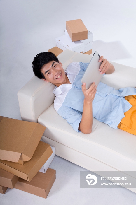 棚拍年轻男人躺在沙发上玩平板电脑