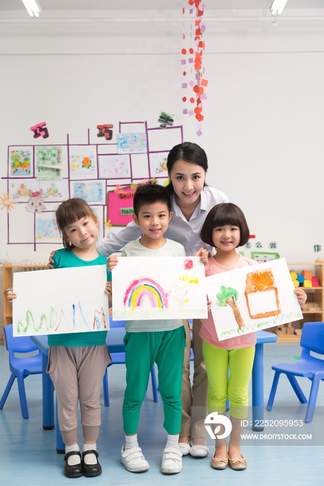 幼儿园女老师和儿童展示绘画作品