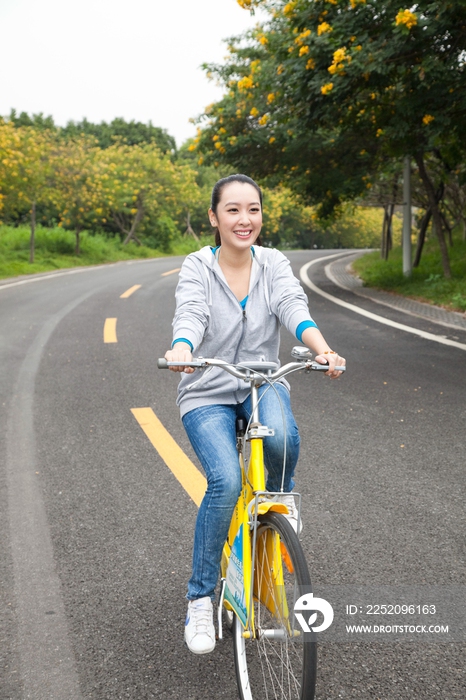 一个年轻女大学生在校园里骑车