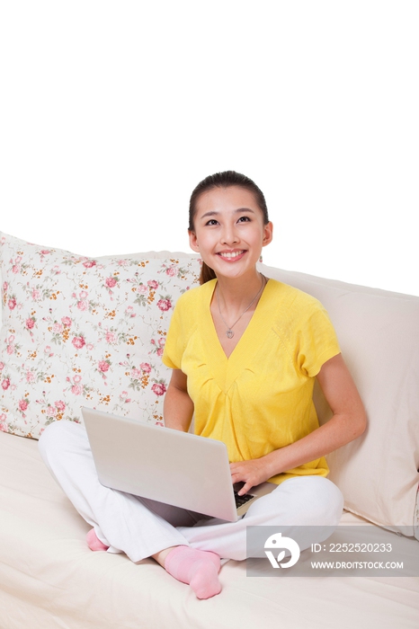 年轻女人坐在沙发上使用笔记本电脑