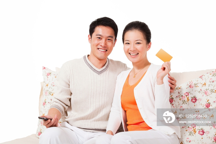 幸福的夫妻坐在沙发上展示信用卡