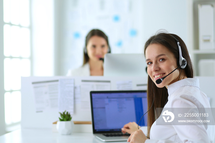 Smiling businesswoman or helpline operator with headset and computer at office