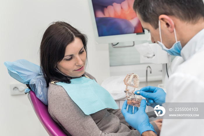 Woman in dentistry looking at model of prosthesis