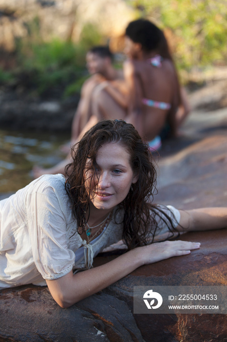 Sensual young woman relaxing on wet rocks