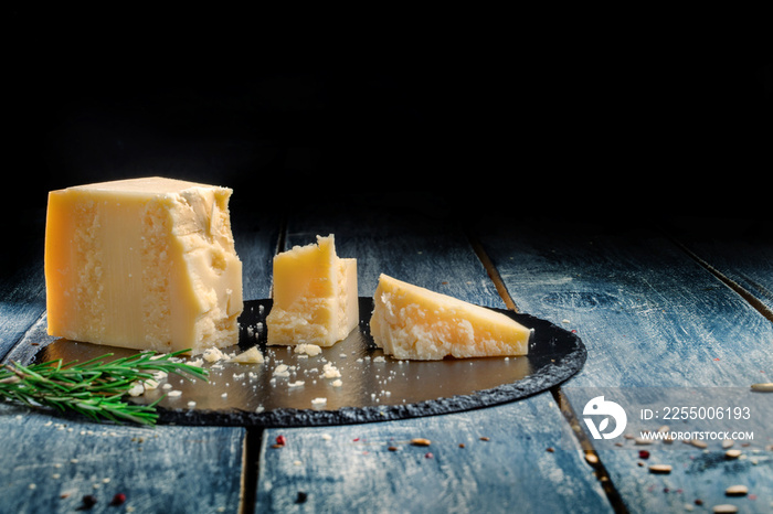 Pieces of parmesan or parmigiano cheese on a wooden dark board