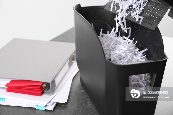 Document shredder with paper shreds on table, closeup