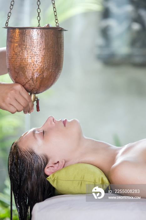 Shirodhara, an Ayurvedic healing technique. Oil dripping on the female forehead. Portrait of a young