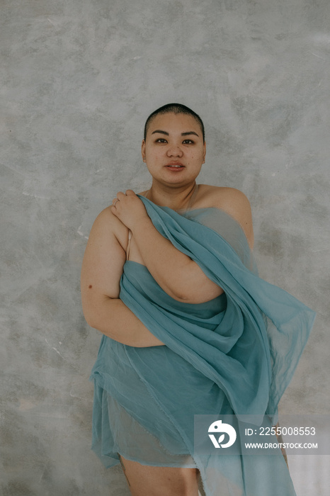 vertical portrait of a plus size filipino woman with a shaved head looking forward