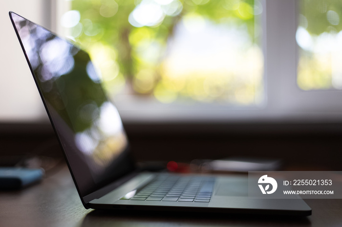 Close-up of modern laptop on background of window.