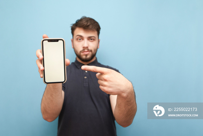 Smartphone with a blank white screen in the hands of an adult man with a beard, wearing a dark shirt