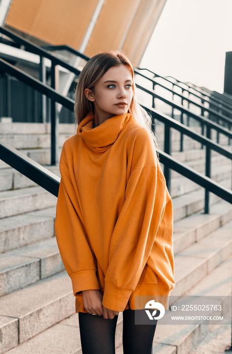 Fashion young woman posing near steps. Wearing in orange jacket. Street urban style. Beauty blonde g