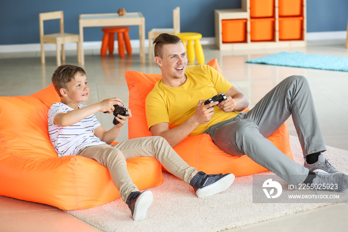 Portrait of father and son playing video game at home