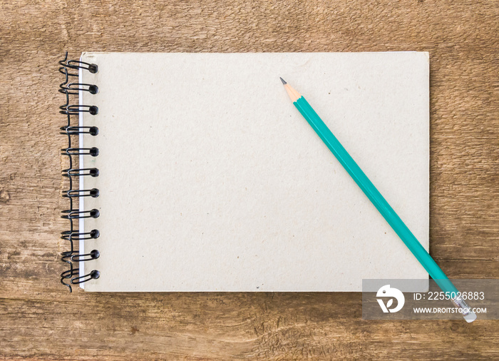 Blank paper and green pencil on the wooden table. View from above