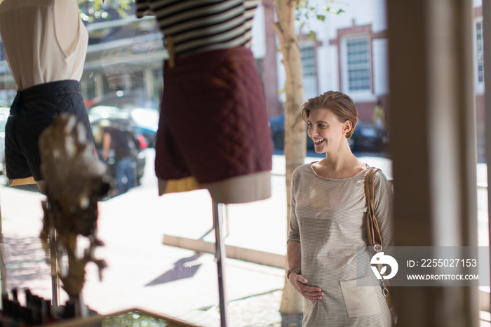 Pregnant woman window shopping outside shop