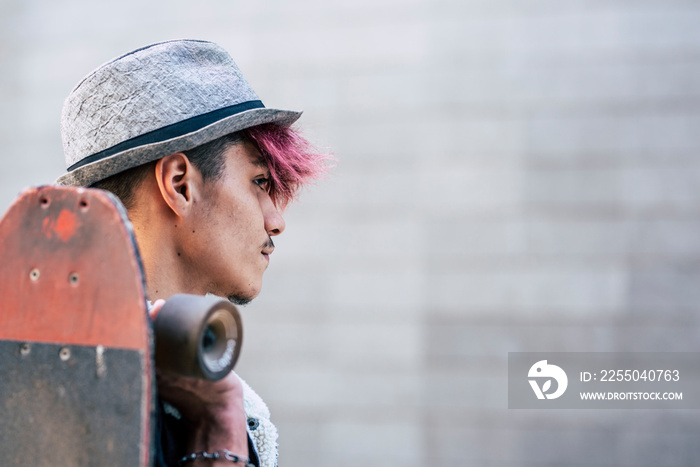 Portrait of handsome young teenager man boy looking in front of him and holding a skateboard - diver