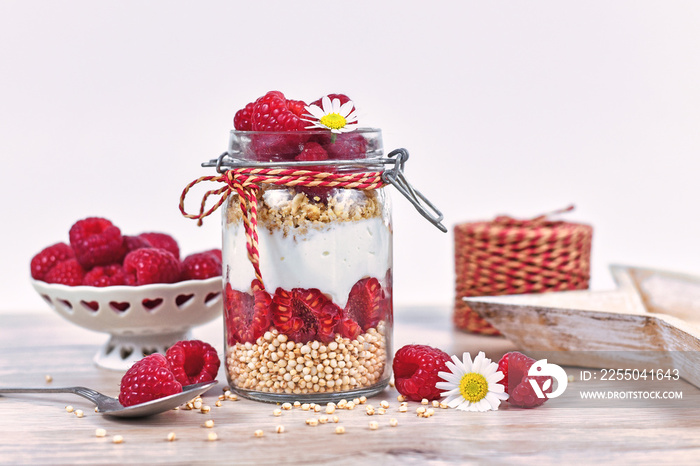 Healthy raspberry fruit dessert with skyr yogurt, granola and puffed quinoa grains layered in jar su
