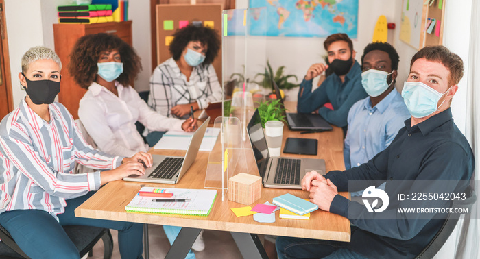 Young people working inside coworking office while wearing protective masks for coronavirus spread p