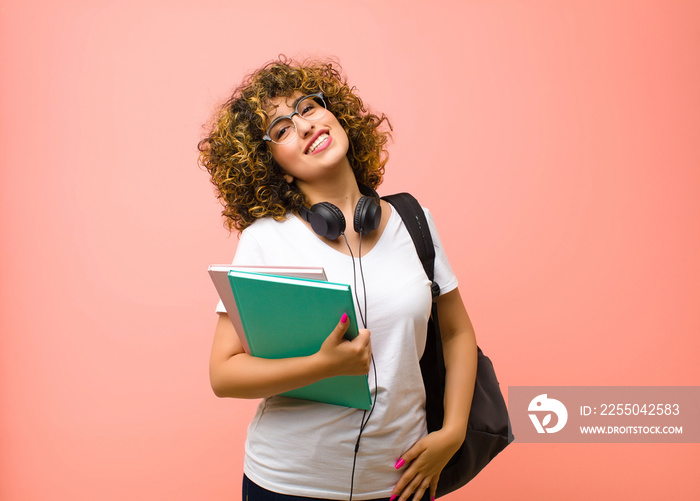 young pretty student woman smiling cheerfully and casually with a positive, happy, confident and rel