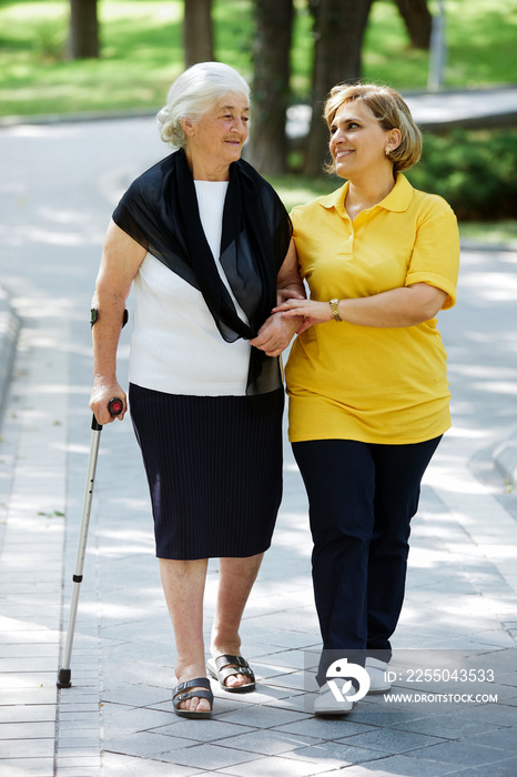 Professional caregiver taking care of senior woman, outdoors.