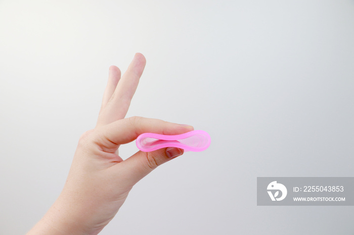 A woman holds a menstrual cup in her hand on a pink background. The concept of womens health, hygie