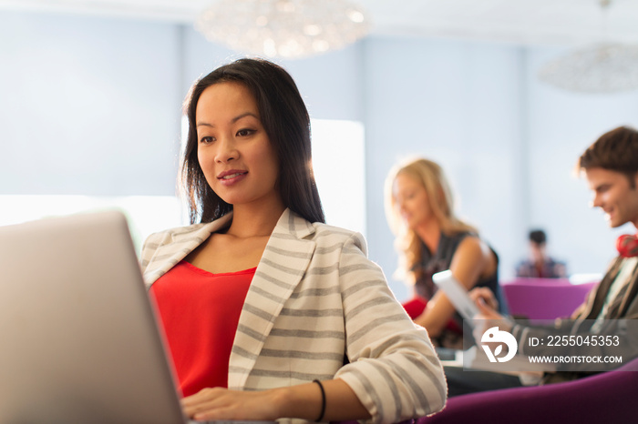 Female college student using laptop in student lounge