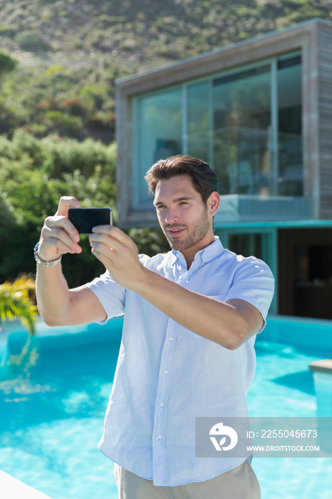 Young man using smart phone at sunny poolside