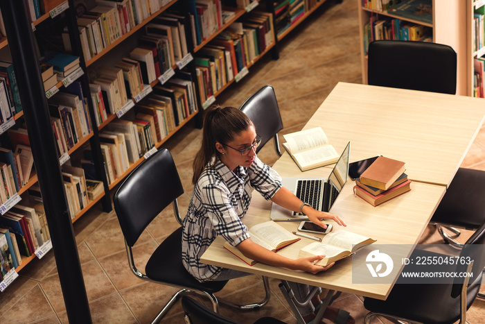 Young female student study in the library using laptop for researching online.