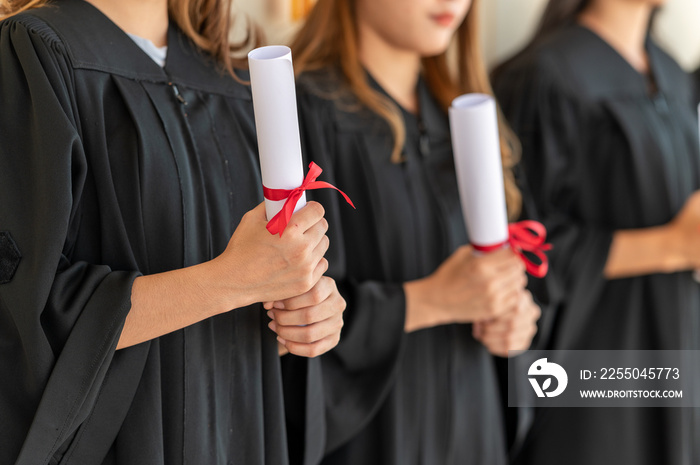 group of graduates Asian student in academic gown and graduation holding diploma certificates