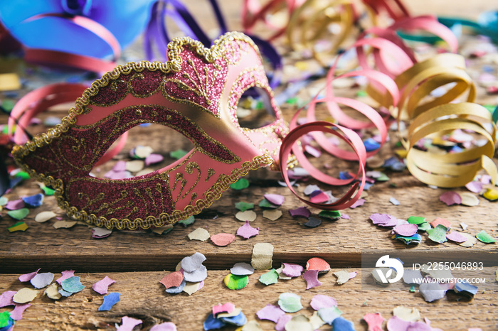嘉年华派对。面具、五彩纸屑和木制背景上的蛇形图案
