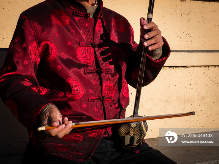 Asian senior man playing an erhu in the street