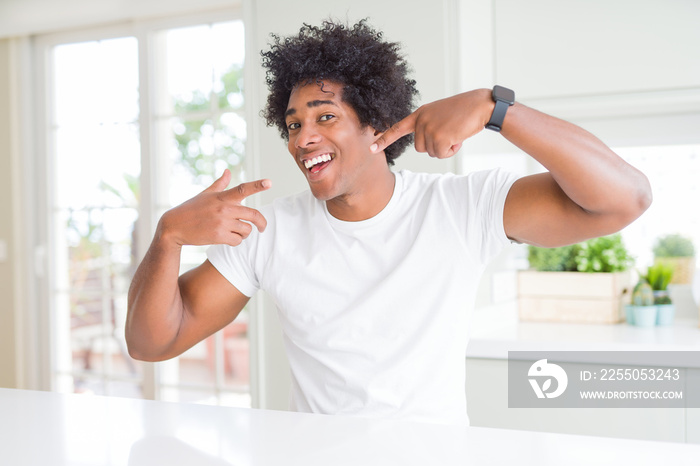 Young african american man wearing casual white t-shirt sitting at home smiling cheerful showing and