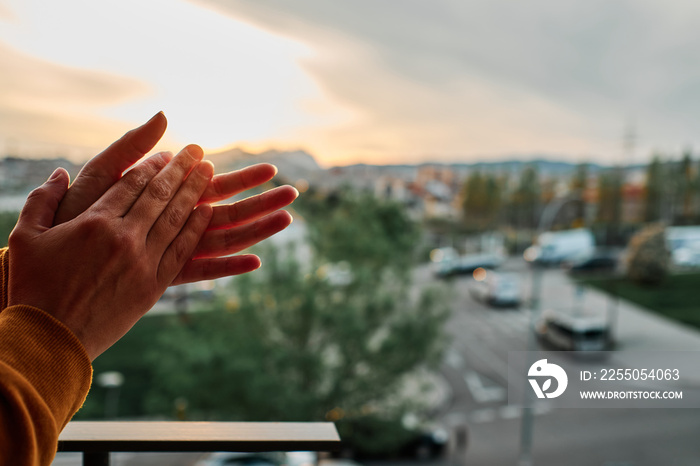 a woman claps her hands to congratulate healthcare system in Spain during coronavirus outbreak