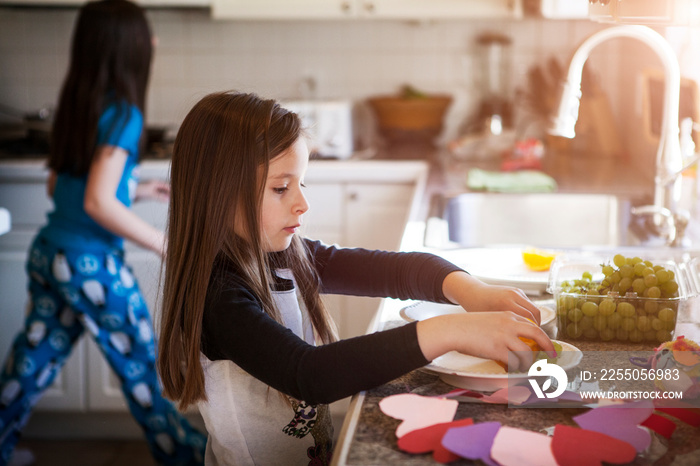 Girl keeping grapes on plate in kitchen at home