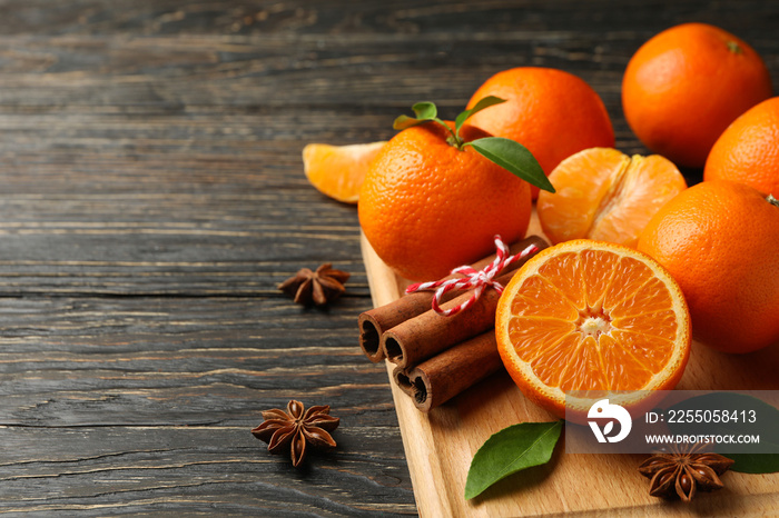 Board with mandarins and cinnamon on wooden background