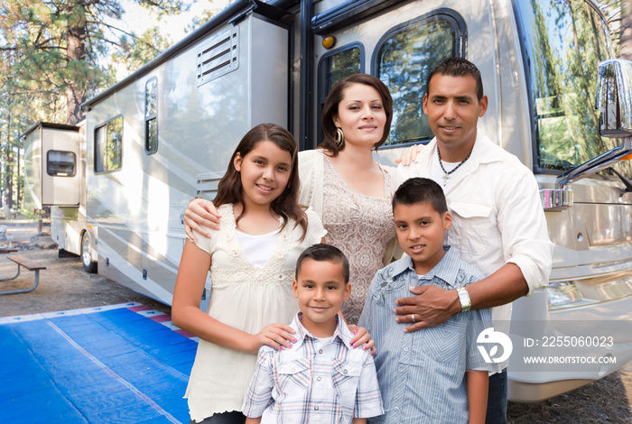 快乐的西班牙裔家庭在露营地美丽的房车前。